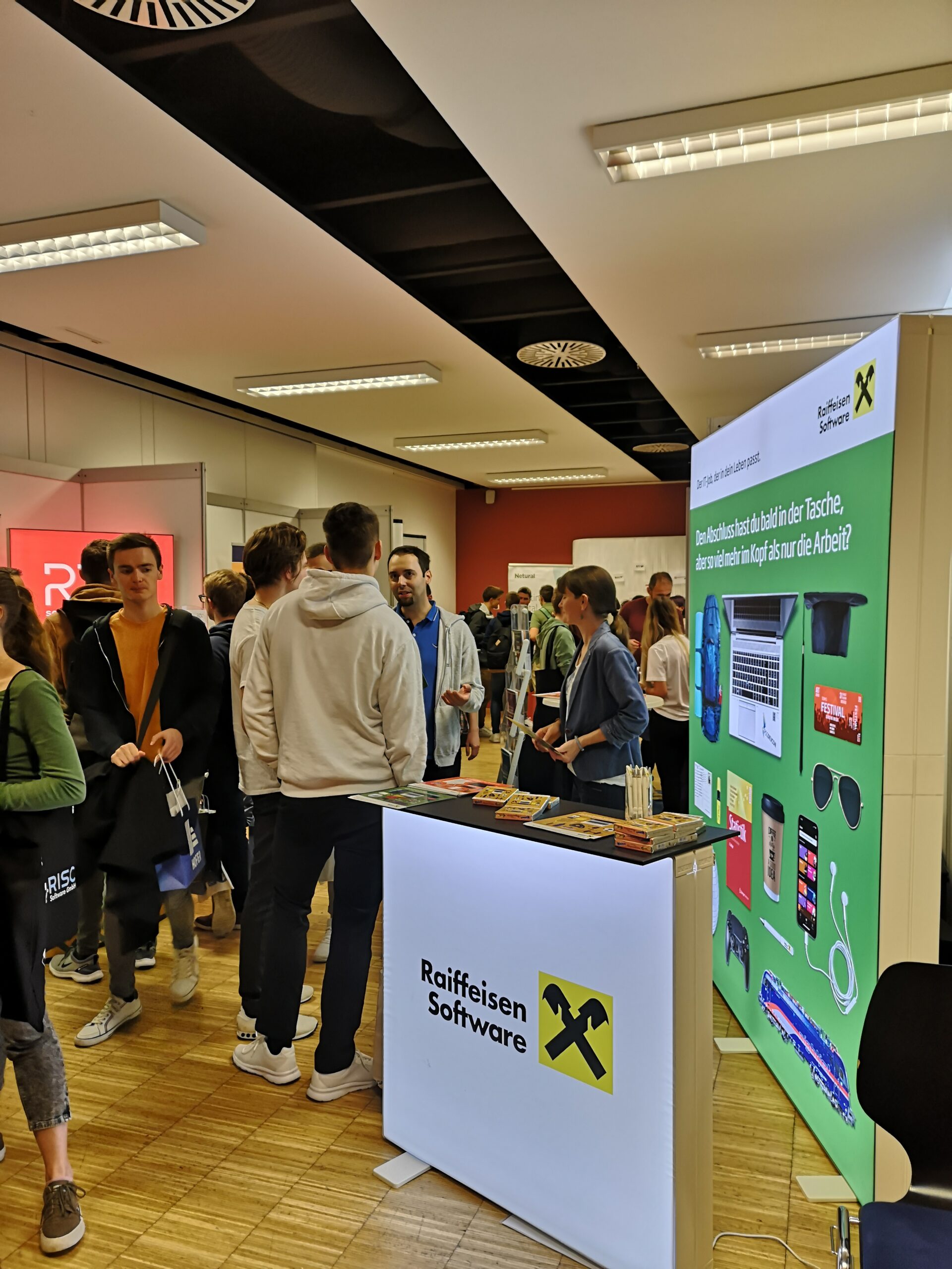 Gruppe von jungen Menschen unterhält sich vor Messestand