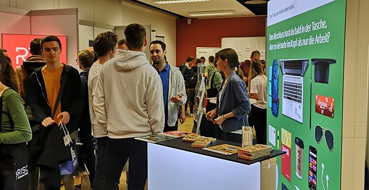 Gruppe von jungen Menschen unterhält sich vor Messestand