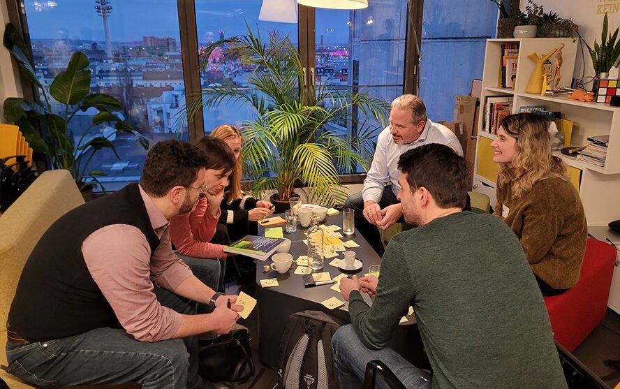 Gruppe von Menschen sitzend um einen Tisch beim Ideen sammeln