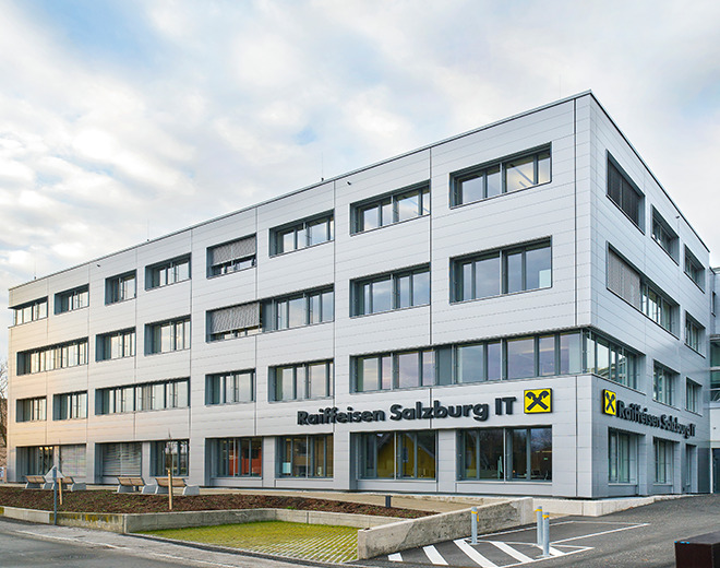 Modernes Bürogebäude mit der Aufschrift ‚Raiffeisen Salzburg IT‘ und dem Raiffeisen-Logo an der Fassade.